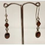 A pair of modern design silver drop earring set with garnets.