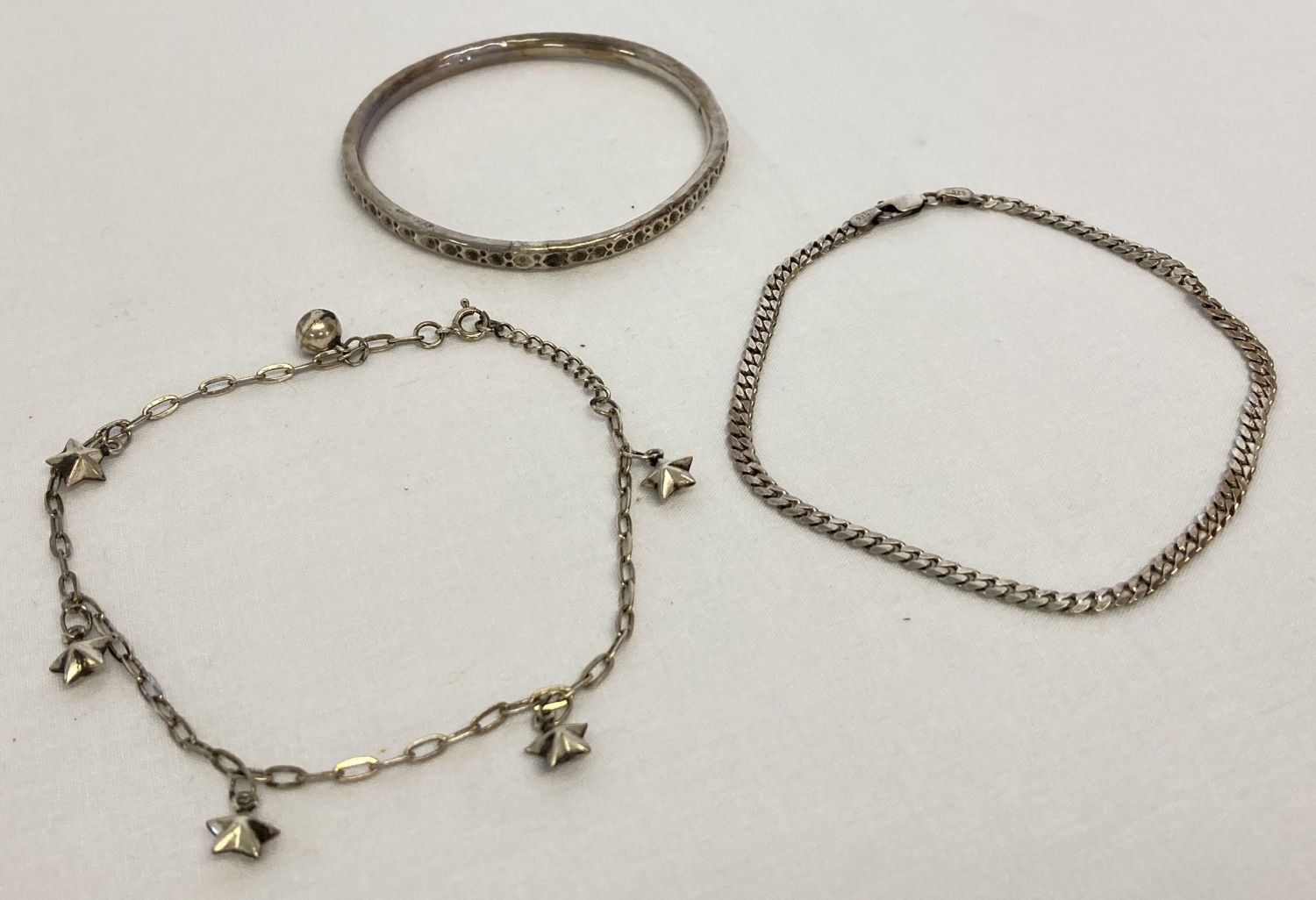 2 silver ankle chains, a curb chain and a decorative chain with star charms.