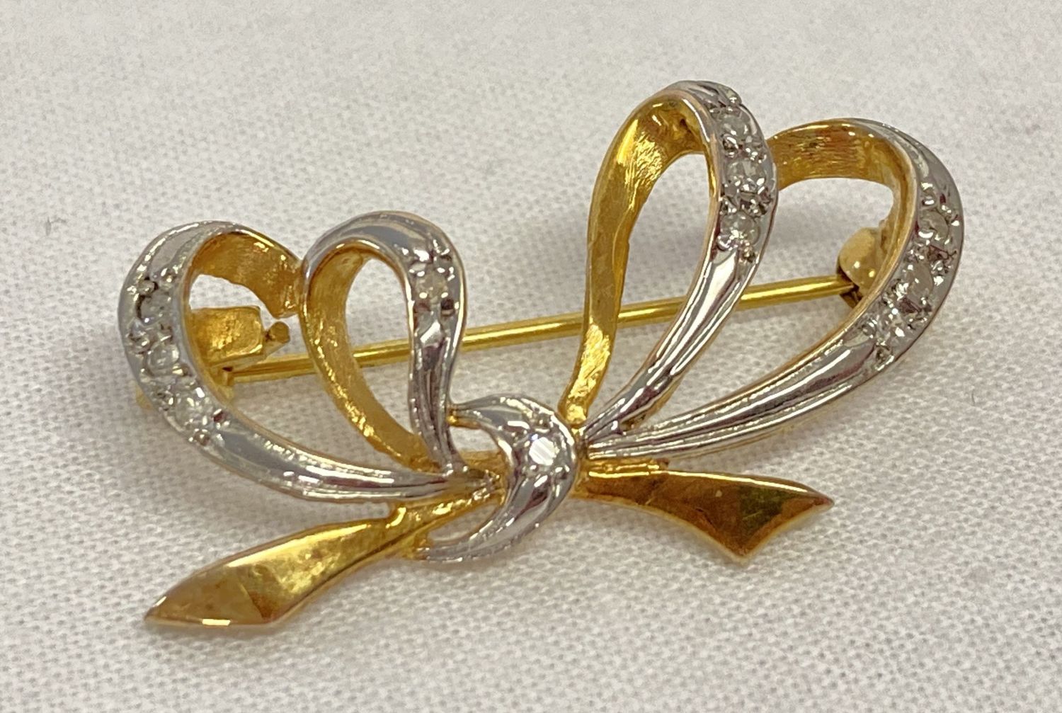 A 9ct white and yellow gold bow design brooch set with 11 small round cut diamonds.