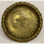 A WWII style brass pin tray/coin dish with N.S.F.K paramilitary insignia embossed into base.