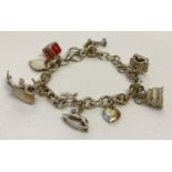 A silver charm bracelet with t bar clasp and 9 silver and white metal charms.