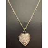 A silver heart shaped locket with floral decoration to front, on a 24" rope chain.