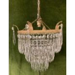 A vintage French style 3 tier crystal and brass chandelier with 6 decorative brass leaf overhangs.