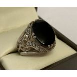 A silver dress ring set with oval cut onyx and small marcasites to decorative mount.