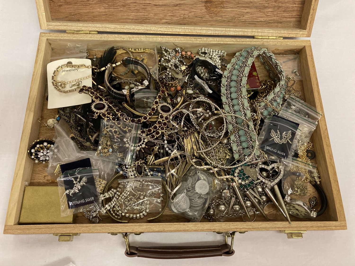 A wooden box containing a quantity of vintage and modern costume jewellery to include diamante.