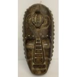 A carved wooden tribal mask with serpent detail to front.