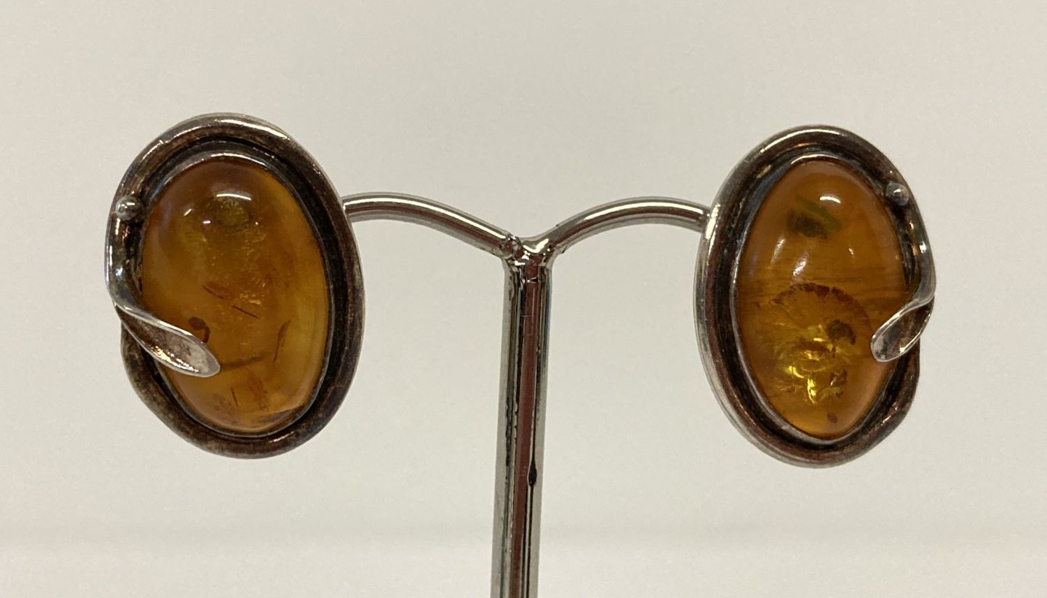 A pair of silver and amber stud style earrings with Art Nouveau style decoration.