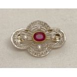 An Art Deco style, open pierced work design 9ct gold brooch, set with diamonds and a central ruby.