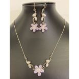 A silver flower design necklace and matching drop earrings, set with clear and pale lilac stones.