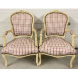 A pair of wooden framed Louis XV style low armchairs, painted cream.