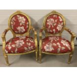 A pair of gilt framed Louis XV style armchairs with red floral upholstery.