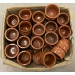 A box containing 51 small terracotta glazed pots.