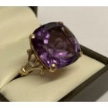 A 9ct gold amethyst and diamond dress ring with large cushion cut central amethyst.