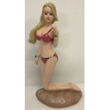 A painted cast metal doorstop in the shape of a bikini clad woman.