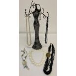 A jewellery stand in the shape of a evening dress together with a small collection of necklaces.