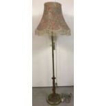 A brass covered standard lamp with Art Nouveau style lotus flower and leaf design to base.