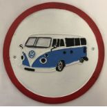 A circular shaped painted cast iron wall plaque depicting a VW camper van.