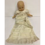 A modern baby doll with cloth body and vinyl head, hands and body, in a vintage christening gown.