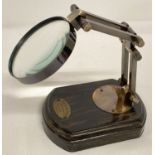 A desk top adjustable magnifying glass on wooden bass with "Watts & Sons Ltd" brass plaque.