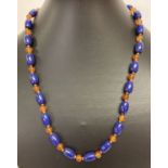 A 19" blue stone and carnelian beaded necklace with gold tone T bar clasp.