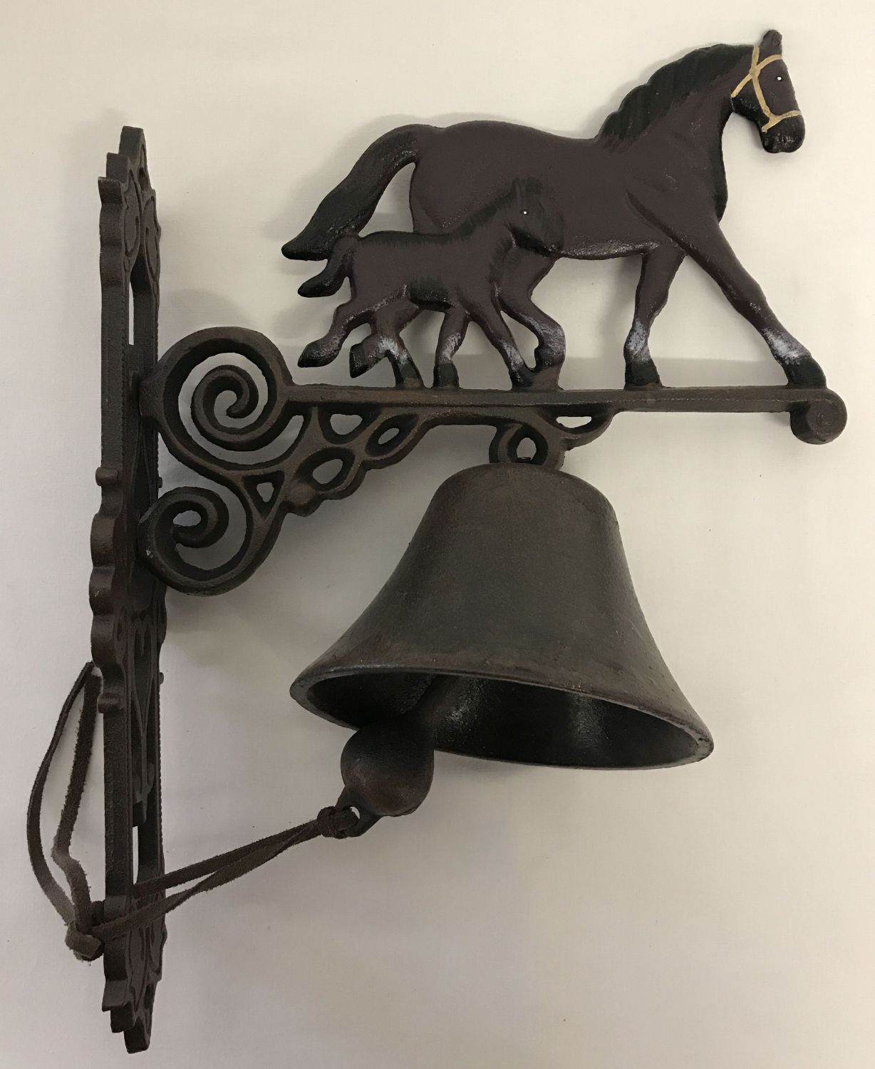 A cast metal wall hanging garden bell with horse and foal decoration.