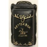 A cast metal wall hanging letter box, painted black with gold detailing and hinged opening lid.