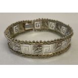 A flexible silver panel bracelet with owl and Greek key decoration. Clasp needs attention.