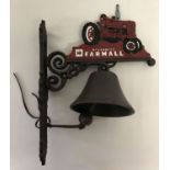 A cast metal wall hanging garden bell with McCormick Farmall tractor decoration.