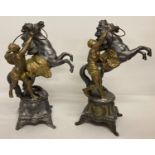 2 cast metal figures of a man holding a rearing horse.