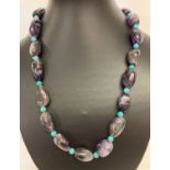 A 20" amethyst and turquoise beaded necklace with white metal S shaped clasp.