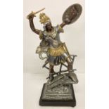 A large cast metal figure of a centurion standing on a bridge on a black fixed plinth with bun feet.