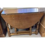 A solid wood drop leaf gate leg table with turned legs.