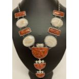 A large white metal statement necklace set with mother of pearl, keshi pearl and red stones.