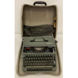 A vintage Olympia typewriter complete with protective cover, cleaning brush and carry case.
