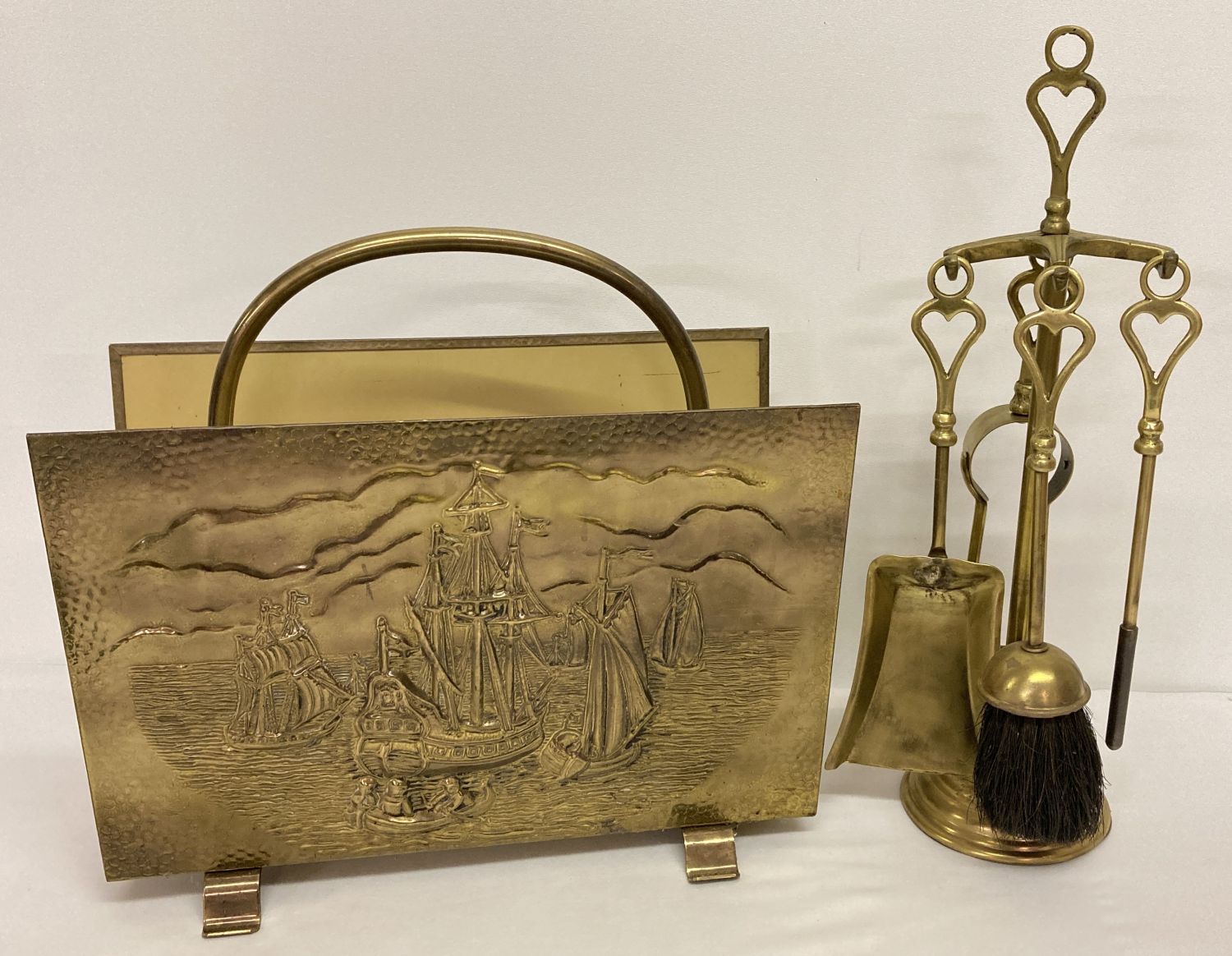 A vintage brass magazine rack with embossed ship decoration together with a vintage brass companion