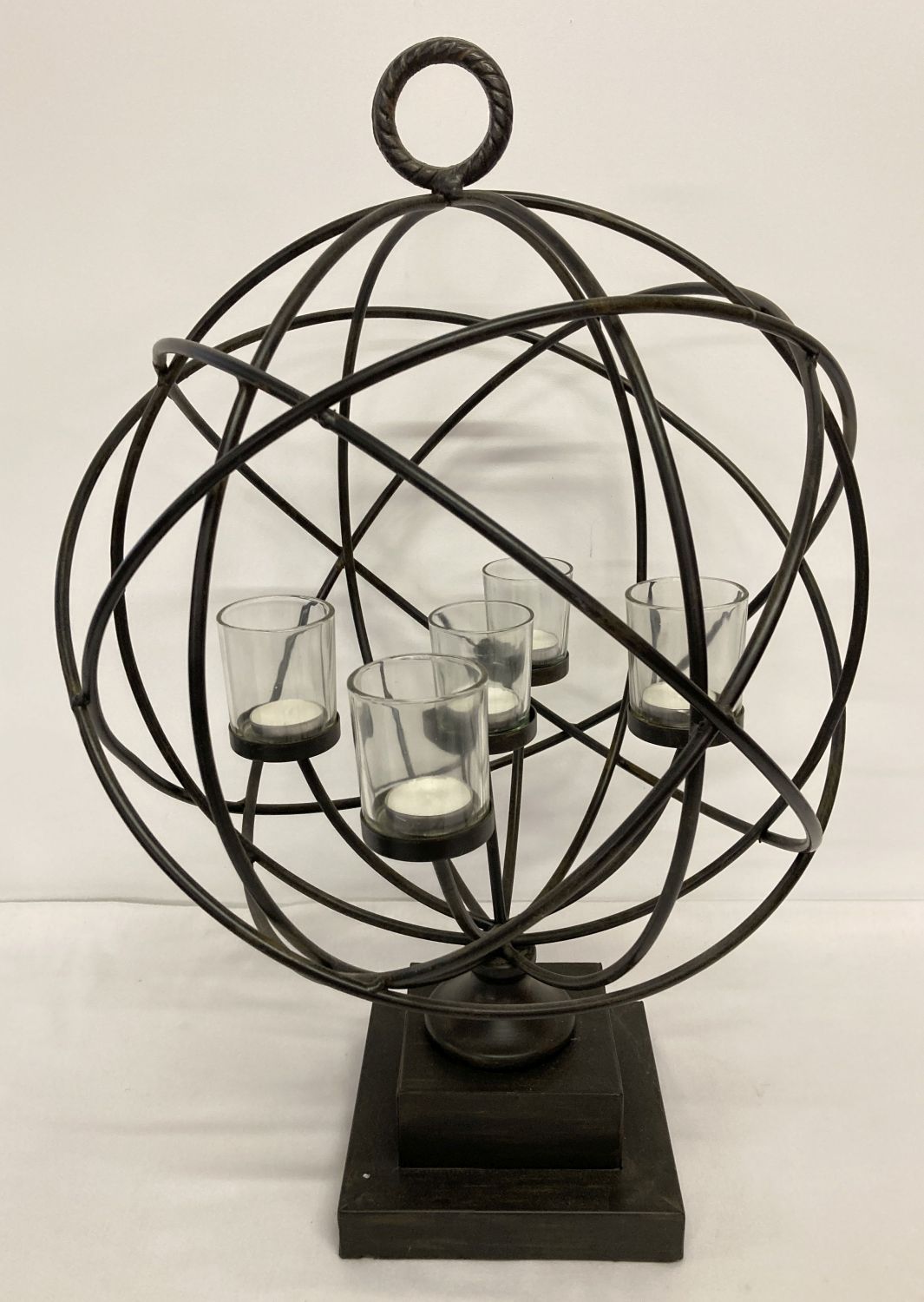 A large black metal spherical shaped freestanding candle holder with glass cups and tealights.