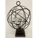A large black metal spherical shaped freestanding candle holder with glass cups and tealights.