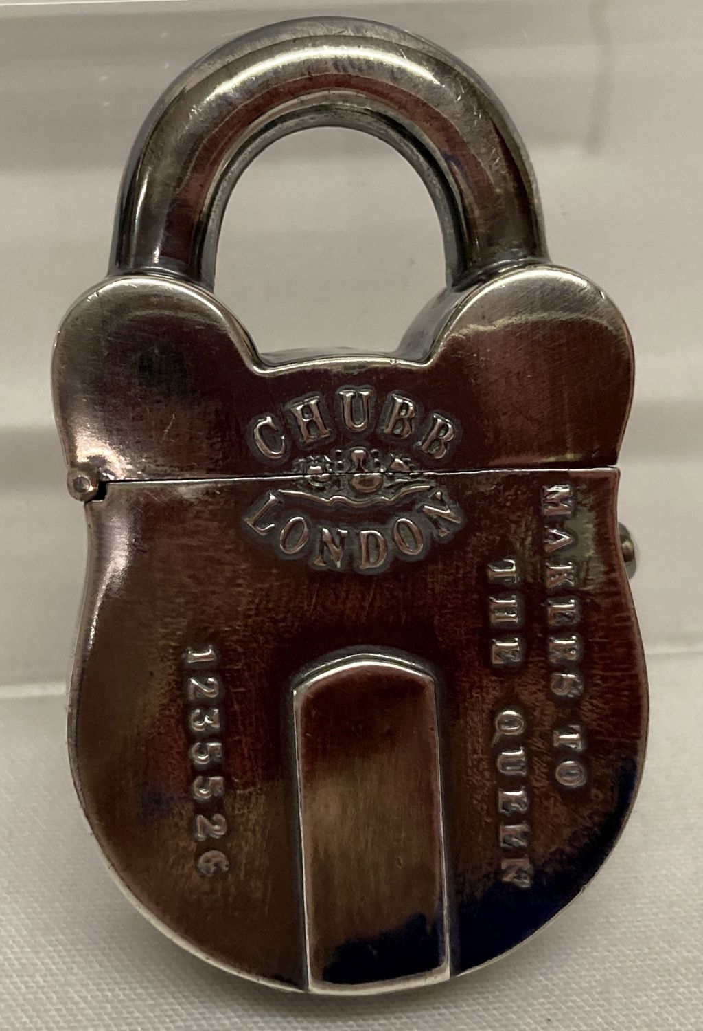 A white metal vesta case in the shape of a padlock, with push button opening.