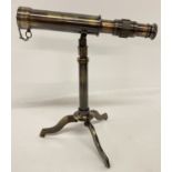 A small brass telescope mounted on an extending tripod base with folding feet.