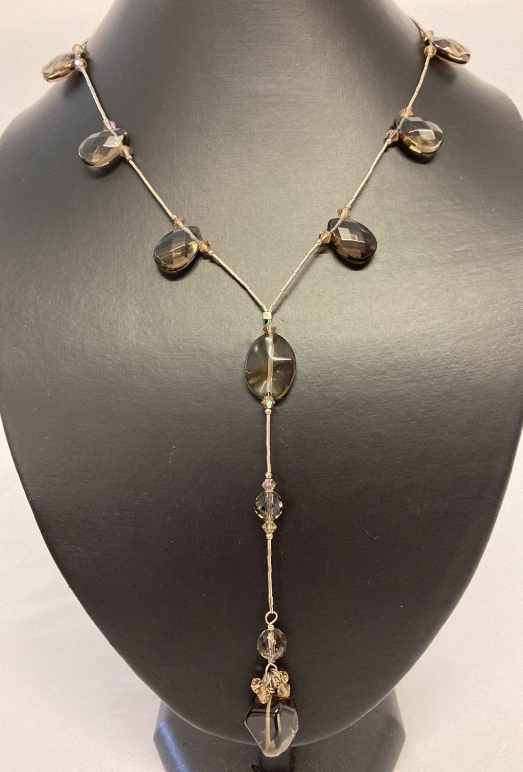 A modern design, faceted smoked glass drop style necklace with silver clasp.