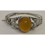 A Polish silver decorative bangle set with central Baltic amber cabochon with push clasp.