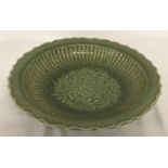 A large celadon glaze stoneware shallow bowl with floral and bird detail to inner bowl.