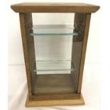 A small free-standing wooden table-top display cabinet.