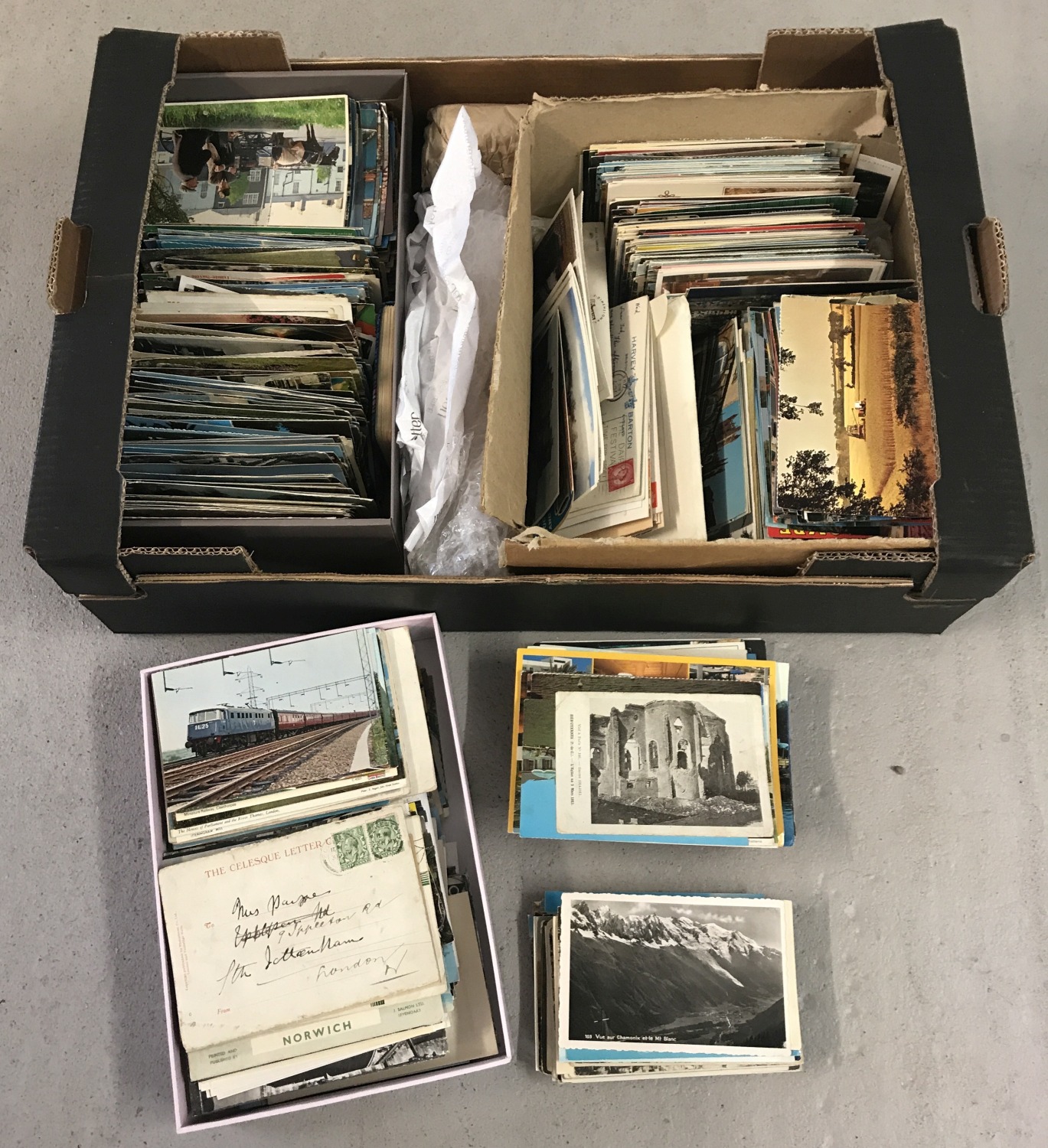 A large box of assorted vintage and modern postcards.