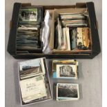 A large box of assorted vintage and modern postcards.