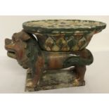 An oriental ceramic pedestal stand in the shape of a foo dog, with majolica style glaze.