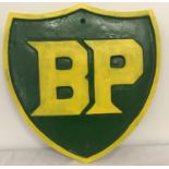 A large green and yellow painted cat iron BP wall hanging plaque.