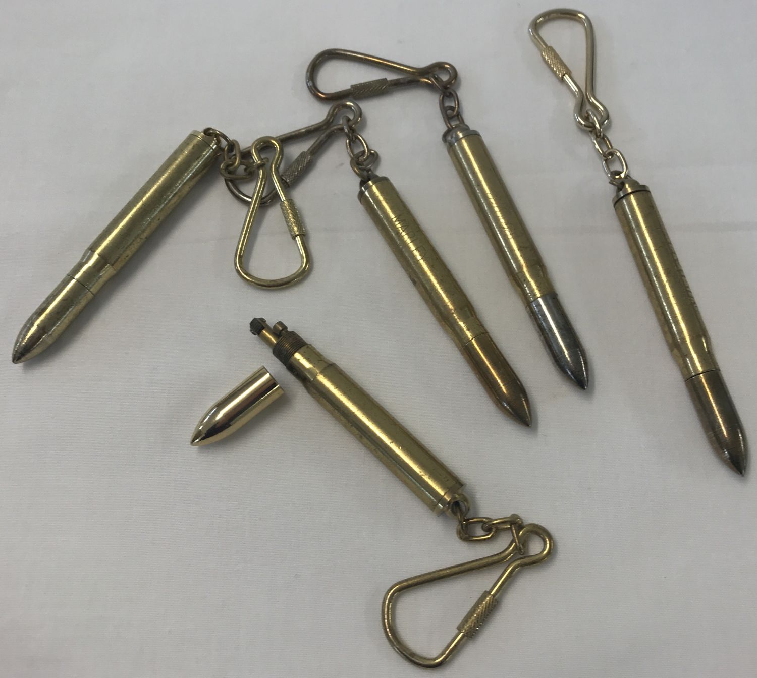 A collection of brass bullet shaped lighters, made into keyrings.