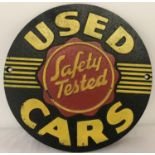 A painted cast metal, circular shaped "Safety Tested Used Cars" wall hanging plaque.