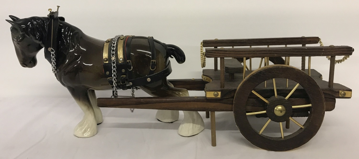 A large ceramic shire horse together with a wooden cart.